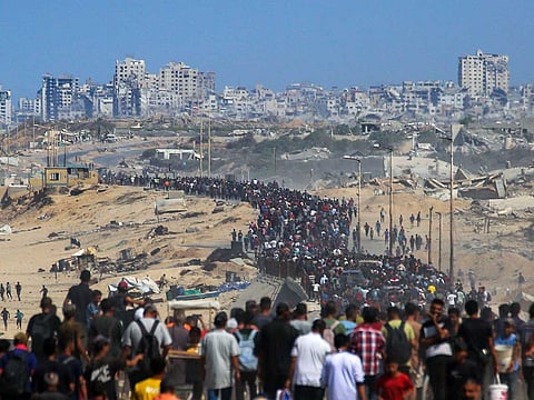 Palestinians walk along Al-Rashid Road toward Gaza City from Nuseirat in the central Gaza Strip on October 10, 2025.