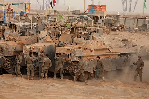 Israeli soldiers gather near armoured vehicles at a position along the Israel-Gaza border fence on October 10, 2025.