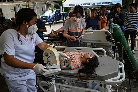 Hospital staff check on a patient outside a damaged hospital in Manay, in the province of Davao Oriental on October 11, 2025, after two powerful quakes struck off the southern Philippines on October 10, killing at least eight people and triggering tsunami warnings.