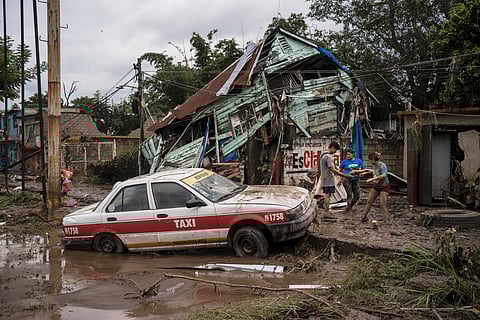 Neighbours gather around a damaged house after heavy rainfall in Poza Rica, Veracruz state, Mexico, Saturday, Oct. 11, 2025.