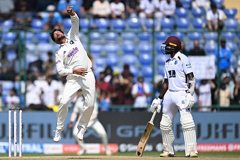 India's Kuldeep Yadav (L) jumps to field the ball as West Indies' Anderson Phillip watches during the third day of the second and last Test cricket match at the Arun Jaitley Stadium in New Delhi on October 12, 2025.