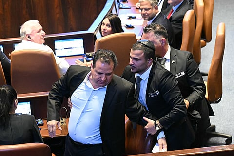 Israeli Knesset member Ayman Odeh is escorted out after holding a sign reading "Recognise Palestine" during a speech by US President Donald Trump at the Israeli parliament, the Knesset, in Jerusalem on October 13, 2025.