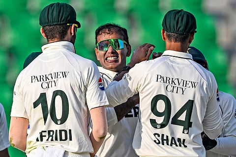 Pakistan's Noman Ali (C) celebrates with teammates after taking he wicket of South Africa's Tristan Stubbs during the second day of the first Test cricket match against South Africa at the Gaddafi Stadium in Lahore on October 13, 2025.
