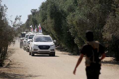 A Palestinian Qassam Brigades militant watches as vehicles of the International Committee of the Red Cross (ICRC) transport 13 hostages handed over by Hamas in the south of Deir el-Balah in the central Gaza Strip, on October 13, 2025.