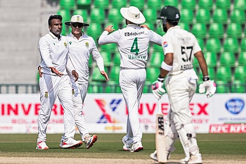 South Africa's Senuran Muthusamy (L) celebrates with teammates after taking the wicket of Pakistan's Abdullah Shafique (R) during the third day of the first Test cricket match at the Gaddafi Stadium in Lahore on October 14, 2025.