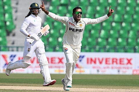 Pakistan's Noman Ali (R) celebrates after taking the wicket of South Africa's Tony de Zorzi (L) during the third day of the first Test cricket match at the Gaddafi Stadium in Lahore on October 14, 2025.