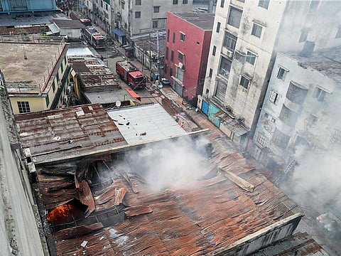 Firefighters douse flames as smoke rises from the burning chemical and garments factory in Dhaka on October 14, 2025.