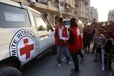 Palestinians and members of the People and members of the International Committee of the Red Cross (ICRC) gather at a site where people are digging with excavators, reportedly in search for bodies in Khan Yunis in the southern Gaza Strip, on October 17, 2025.