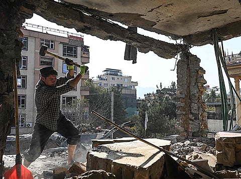 An Afghan man removes debris from a house, which was damaged after an air strike during cross-border clashes between Afghanistan and Pakistan, in Kabul.