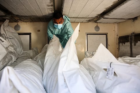 A hospital employee checks the remains of a Palestinians released by Israel under a Gaza ceasefire and hostage exchange deal, inside a refrigerated truck in front of the Nasser hospital in Khan Yunis in the southern Gaza Strip, on October 18, 2025.