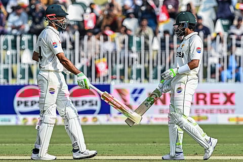 Pakistan's captain Shan Masood (L) and his teammate Babar Azam bump their bats during the first day of the second Test cricket match against South Africa at the Rawalpindi Cricket Stadium in Rawalpindi on October 20, 2025.