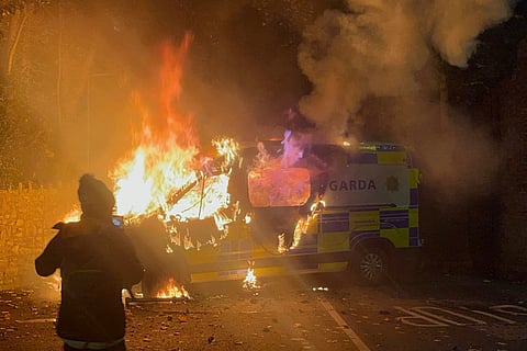 Onlookers film a police vehicle burning as a demonstration outside a hotel housing asylum seekers turns violent in Saggart, south-west of Dublin in Ireland on October 21, 2025.
