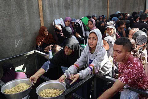Palestinian children gather to receive food portions from a charity kitchen in the Nuseirat refugee camp, located in the central Gaza Strip, on October 21, 2025, a week after a ceasefire came into effect.