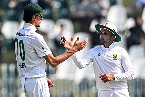 South Africa's Keshav Maharaj (R) celebrates with Marco Jansen after taking his seventh wicket of Pakistan's Asif Afridi during the second day of the second Test cricket match at the Rawalpindi Cricket Stadium in Rawalpindi on October 21, 2025.