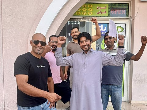 Saud Afzal (left) and his brother celebrate with the grocery’s employees