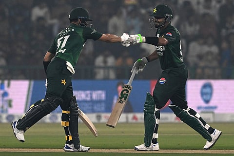 Pakistan's Sahibzada Farhan (L) and Babar Azam (R) bump up during the third and final Twenty20 international cricket match between Pakistan and South Africa at the Gaddafi Stadium in Lahore on November 1, 2025.