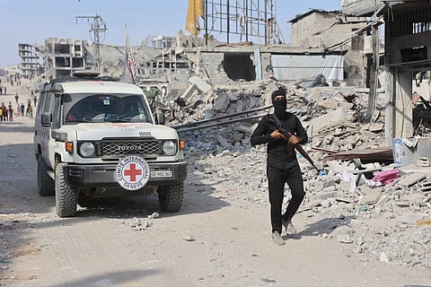 An armed Palestinian Hamas militant stand not far from an International Red Cross (ICRC) vehicle, as a search for the bodies of killed Israeli hostages takes place, in Gaza City on November 2, 2025.
