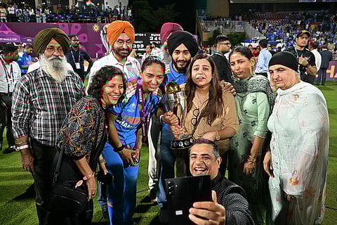 India's captain Harmanpreet Kaur (C) poses with her family members after winning the ICC Women's Cricket World Cup 2025 one-day international (ODI) final match between India and South Africa at the DY Patil Stadium in Navi Mumbai on November 3, 2025.