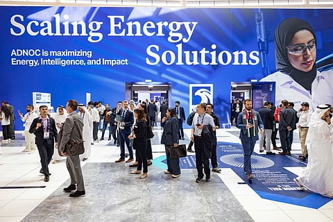 Attendees near an ADNOC advertisement at the ADIPEC conference in Abu Dhabi, United Arab Emirates, on Monday, Nov. 3, 2025. The annual strategic energy conference runs from Nov 3-6.