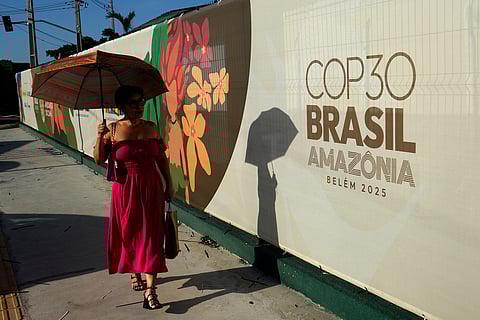 A woman walks past a sign for the COP30 UN Climate Summit, in Belem, Para state, Brazil, Tuesday, November 4, 2025.