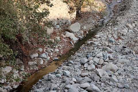 A trickle of water flows in the mainly dried-up Kan River, west of Tehran on November 9, 2025, as the Iran faces sever water shortages.