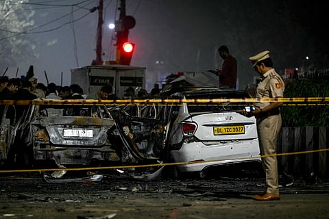 A police personnel inspects charred vehicles at the blast site after an explosion near the Red Fort in the old quarters of Delhi on November 10, 2025.