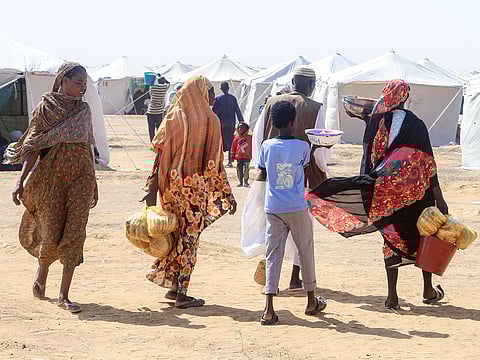 Sudanese people who fled Al-Fashir prepare a meal at a camp for the displaced in the northern town of Al-Dabba on November 13, 2025.