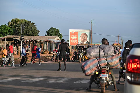 Pedestrians cross a street in Boundiali, northern Ivory Coast, on November 1, 2025 where Ivorians truck drivers refuse to go to Mali due to militant attacks.