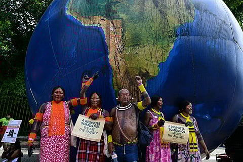 Indigenous people pose next to a giant inflatable globe during the "Indigenous People Global March" at the COP30 UN Climate Change Conference in Belem, Para state, Brazil, on November 17, 2025.