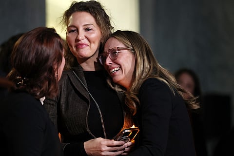 Laura Bloom McGee (C) and Annie Farmer (R), survivors of convicted sex offender Jeffrey Epstein, react after receiving word that the US Senate unanimously approved release of the Epstein files on Capitol Hill November 18, 2025 in Washington, DC. The House had previously voted 427-1 to approve the bill.