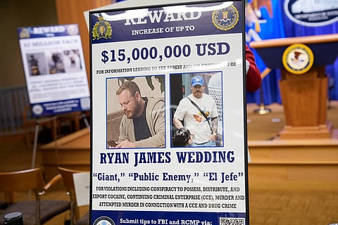 A reward poster for the arrest of Ryan James Wedding is visible following a news conference announcing the indictment of a former Olympic snowboarder Ryan Wedding, charging him with murder and money laundering in connection to a drug trafficking organization at the Justice Department on November 19, 2025 in Washington, DC. The Justice Department announced a fifteen-million-dollar reward for information leading to the arrest of Ryan James Wedding, the leader of a criminal drug organization who smuggled large quantities of cocaine through Colombia and Mexico for distribution in the United States and Canada.