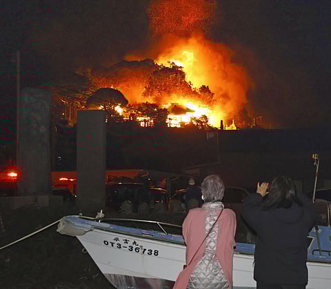 Residents watch flames rise from the site of a fire in Oita, southern Japan Tuesday, Nov. 18, 2025.