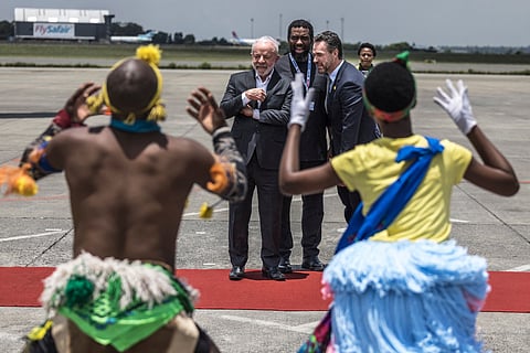 Brazil's President Luiz Inacio Lula da Silva (C) and South Africa's Higher Education Minister Buti Manamela (C-R) react as they watch the Umzekelo cultural group perform upon his arrival at the OR Tambo International airport in Ekurhuleni on November 21, 2025 ahead of the G20 leader's Summit.