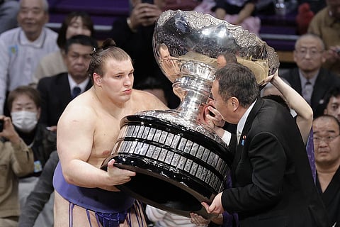 Ukrainian Aonishiki, left, receives a trophy after winning the Kyushu Grand Sumo Tournament in Fukuoka, western Japan, Sunday, Nov. 23, 2025. (Kyodo News via AP)