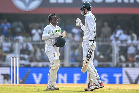 South Africa's Senuran Muthusamy (L) celebrates with teammate Marco Jansen after scoring a century (100 runs) during the second day of the second Test cricket match against India at the Barsapara Cricket Stadium in Guwahati on November 23, 2025.