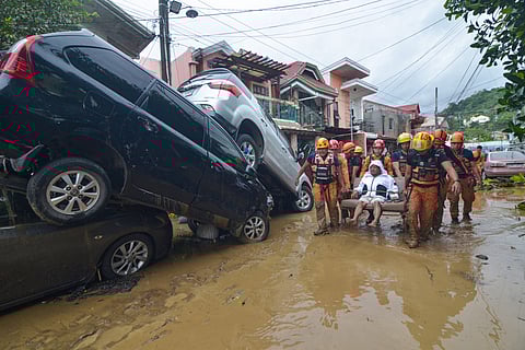 Rescuers carry a resident past cars washed away by floods at the height of Typhoon Kalmaegi at a subdivision of Cebu City in the central Philippines on November 4, 2025.