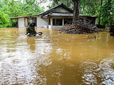 A man wades through floodwaters outside his house after heavy rainfall in Kaduwela on the outskirts of Colombo on November 28, 2025.