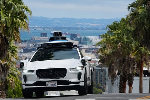 A Waymo car drives up a hill in San Francisco