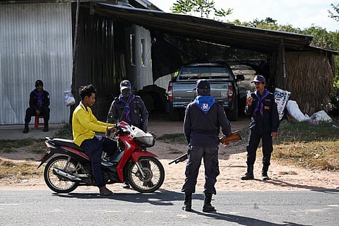 Security volunteers check the identification of a motorist as they remain in the evacuation zone to protect villagers' homes and livestock during the conflict in the Thai province of Buriram, ten kilometres away from the border with Cambodia on December 13, 2025.