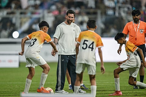 Argentina's footballer Lionel Messi (2L) plays football with children during his GOAT Tour at the Wankhede Stadium in Mumbai on December 14, 2025.