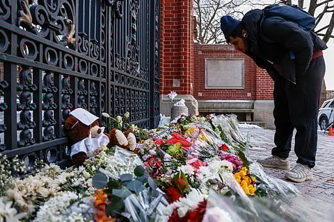 A community member looks at flowers, notes and mementos in a makeshift memorial display sitting in front of Brown University's Van Wickle gates, in Providence, R.I., two days after a shooting took place on the university's campus, Monday, Dec. 15, 2025.
