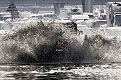 Vehicles drive on a flooded road during heavy rain in the Gulf Emirate of Dubai on December 18, 2025.