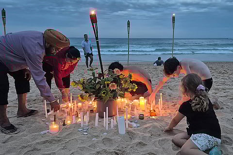 People light candles and lanterns on Manly Beach in Sydney on December 21, 2025, as part of a national day of reflection honouring the victims of the Bondi Beach terrorist attack.