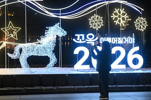 A woman takes a photo in front of a luminous sign for "2026" ahead of a countdown event for the New Year in Seoul on December 31, 2025.