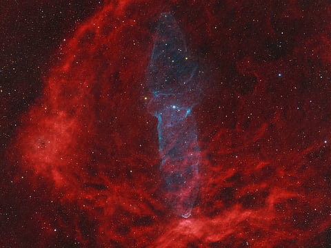 This faint nebula, captured with over 1,800 exposures, reveals its mysterious origins and contrasts beautifully with the brighter Flying Bat Nebula in the foreground.