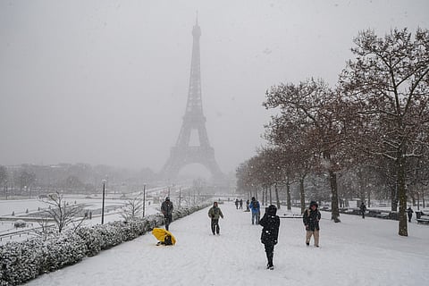 Pedestrians walk on snow at the Trocadero gardens with the the Eiffel Tower in the background during a snowfall in Paris on January 7, 2026.