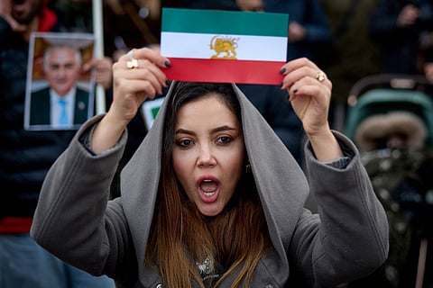 A protester shows an Iran's pre-1979 Islamic Revolution flag during a demonstration to support mass rallies denouncing the Islamic republic in Iran in Paris on January 11, 2026.
