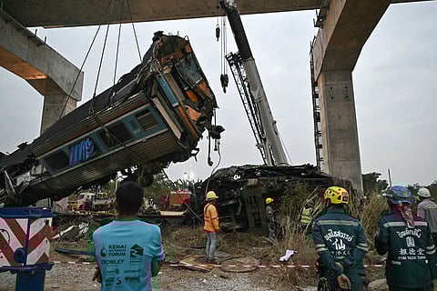 Recovery workers watch as a carriage of a train that crashed when a construction crane collapsed is lifted off the tracks in Thailand's Nakhon Ratchasima province on January 14, 2026.