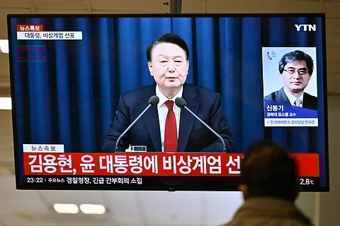 A man watches South Korea's President Yoon Suk Yeol speak during a news broadcast on a television at a train station in Seoul on December 3, 2024, after he declared emergency martial law, saying the step was necessary to protect the country from "communist forces" amid parliamentary wrangling over a budget bill.