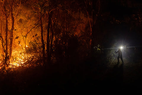 Firefighters battle flames spreading through a forested area near Concepcion, Chile, Tuesday, Jan. 20, 2026. (AP Photo/Javier Torres)